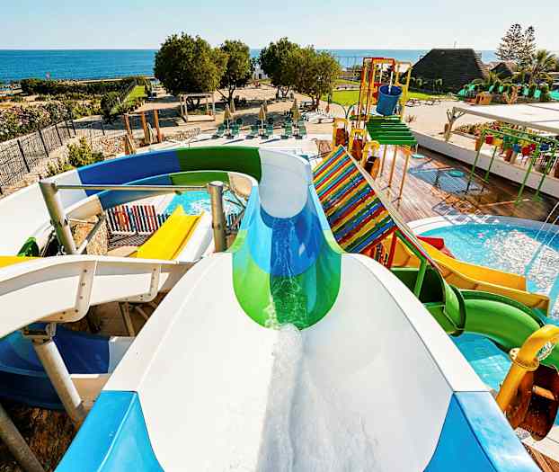 Vandrutsjebaner og poolområde med havet i baggrunden. (AI-genereret tekst)