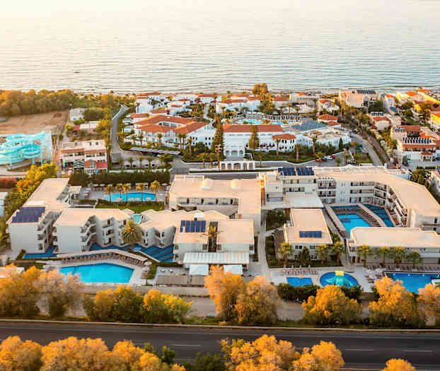 Luftfoto af et feriested med flere pools og vandrutsjebaner ved havet. (AI-genereret tekst)