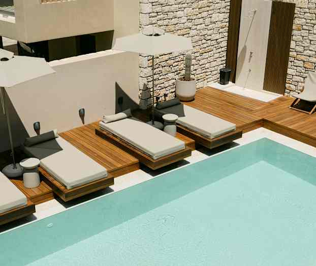 Liggestole ved en swimmingpool på en træterrasse. (AI-genereret tekst)