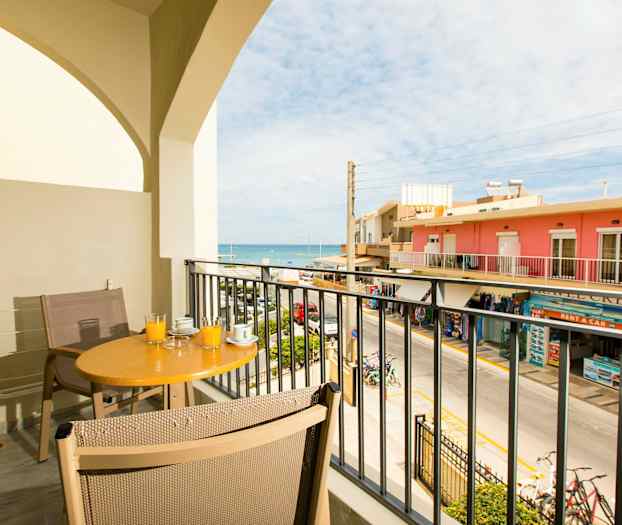 En altan med bord og stole med udsigt over gaden og havet. (AI-genereret tekst)