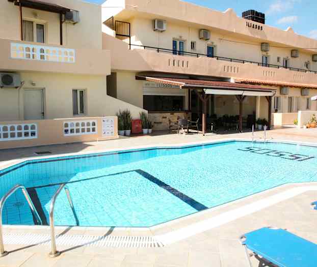 En udendørs pool ved et hotel med liggestole og bygningen i baggrunden. (AI-genereret tekst)