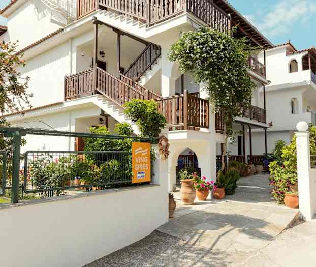 Hvid bygning med trapper og blomsterdekorationer udendørs. (AI-genereret tekst)