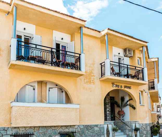 Udvendigt af en gul bygning med altaner og en indgang. (AI-genereret tekst)