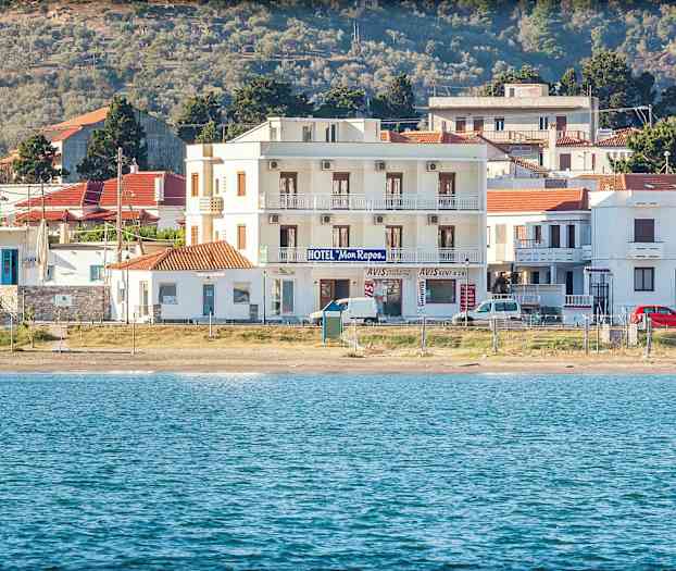 Hotelbygning ved strand med hav i forgrunden. (AI-genereret tekst)