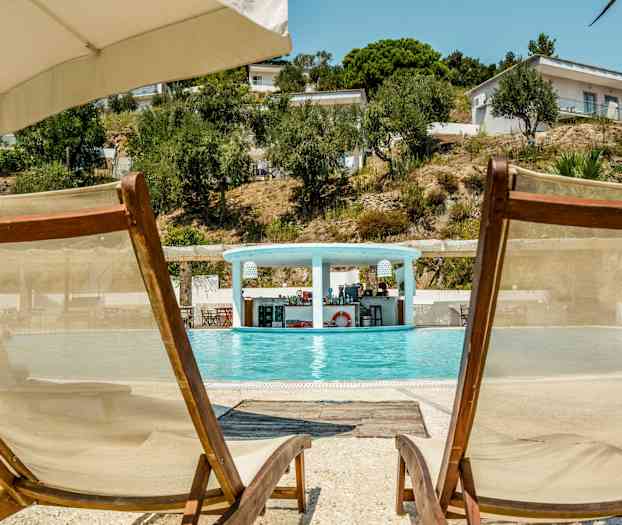 To liggestole ved kanten af en pool med en bar i baggrunden. (AI-genereret tekst)