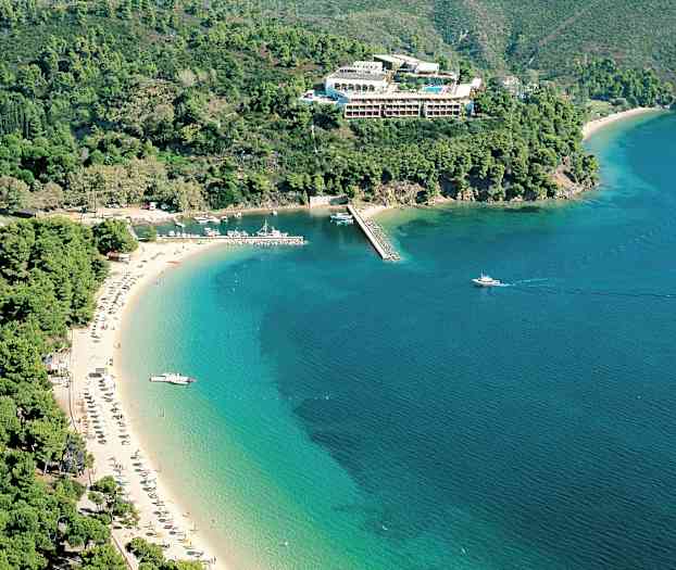 Luftfoto af stranden ved kysten, omgivet af grønne bjerge og hav. (AI-genereret tekst)