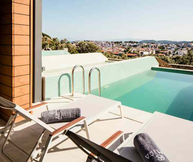 Terrasse med liggestole og en pool med udsigt over en by. (AI-genereret tekst)