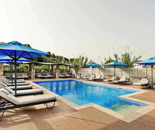 En udendørs pool omgivet af liggestole og parasoller. (AI-genereret tekst)