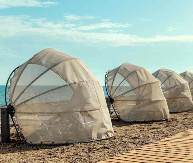 Beskyttede liggestole på stranden nær havet. (AI-genereret tekst)