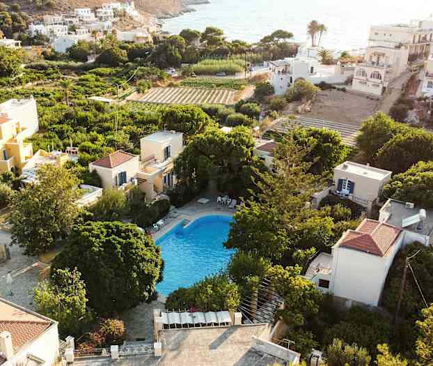 Udsigt over en pool omgivet af grønne områder og huse i et solrigt område. (AI-genereret tekst)