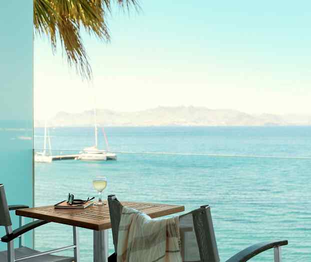 Udsigt over havet fra en altan med bord og stole. (AI-genereret tekst)