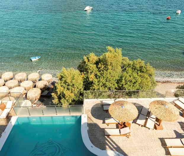 Poolområde med liggestole og parasoller nær stranden og havet. (AI-genereret tekst)