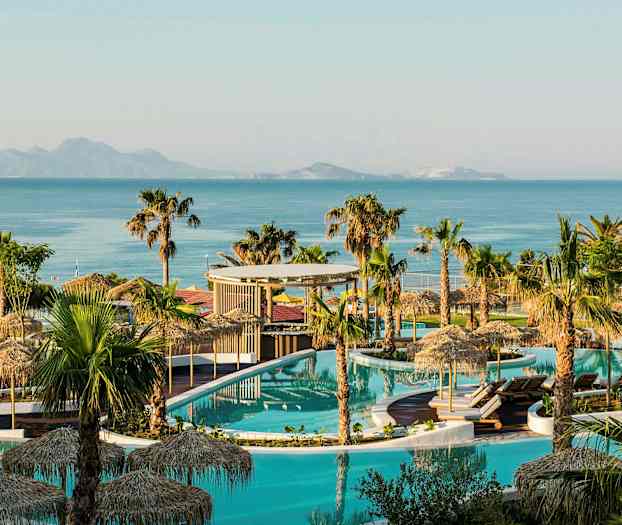 Billede af et poolområde med palmer, parasoller og hav i baggrunden. (AI-genereret tekst)