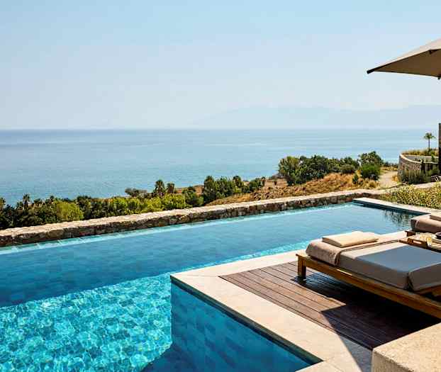 En infinitypool med udsigt over havet og et frodigt landskab. (AI-genereret tekst)