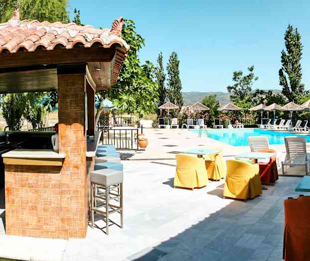 Billede af udendørsområde med en bar og siddepladser, liggestole og en pool. (AI-genereret tekst)