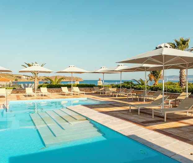 Poolområde med solsenge og parasoller, havudsigt i baggrunden. (AI-genereret tekst)