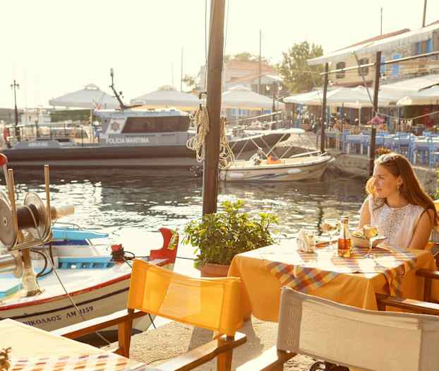 En udendørs restaurant med udsigt over en marina med småbåde og en politibåd. (AI-genereret tekst)