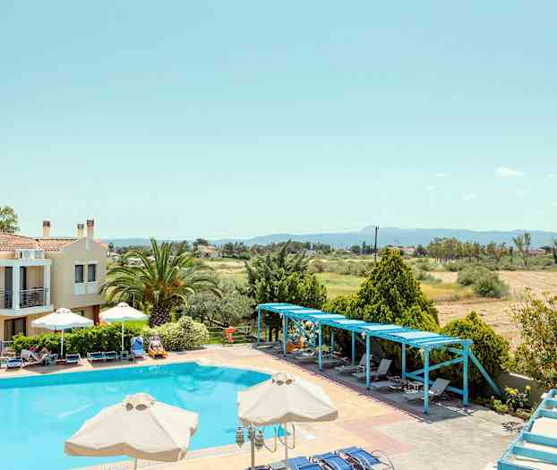 En pool med liggestole og parasoller omgivet af træer og en bygning. (AI-genereret tekst)