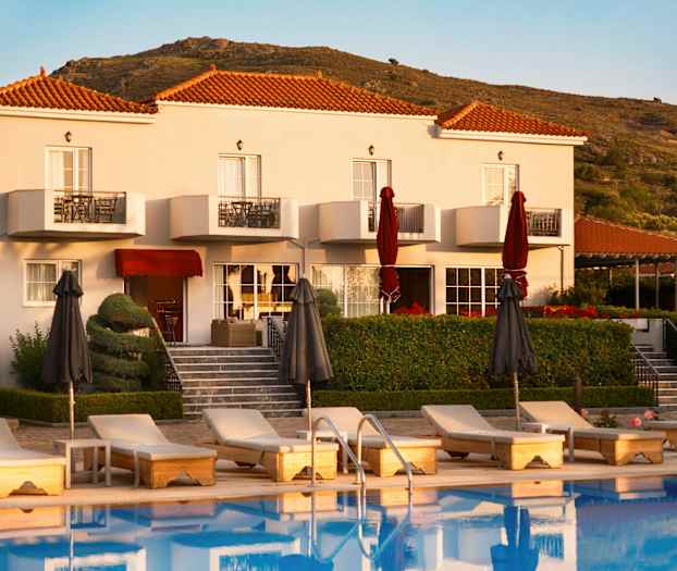 Hotelbygning med pool og liggestole foran samt omkringliggende bakker. (AI-genereret tekst)