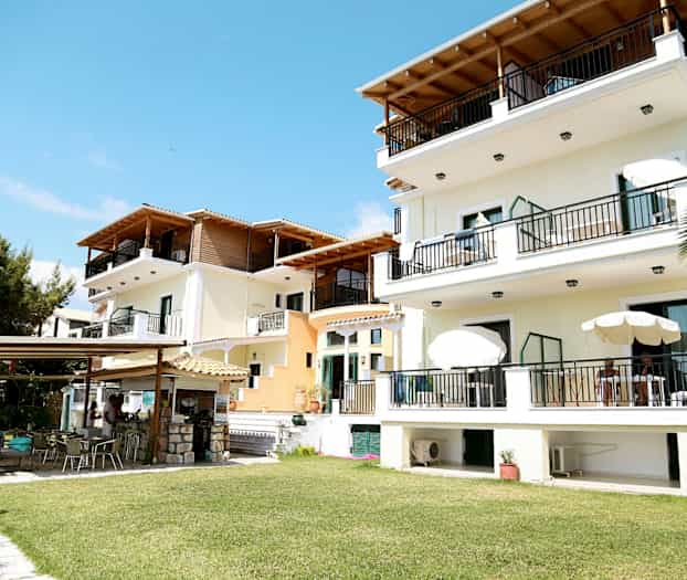 Flere bygninger med altaner og havemøbler, omgivet af grønne græsplæner. (AI-genereret tekst)