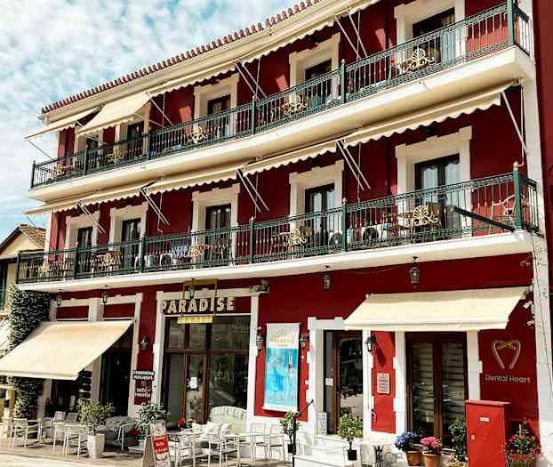 Rød bygning med tre etager, altaner og skilte, inklusive 'Paradise'. (AI-genereret tekst)