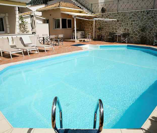 Udendørs pool med liggestole og parasoller ved siden af. (AI-genereret tekst)