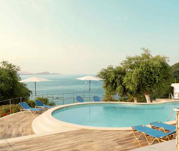 Udendørsområde med en pool, liggestole og udsigt over havet. (AI-genereret tekst)