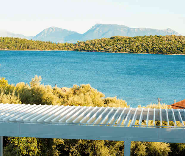 Udsigt over havet med træer og en terrasse i forgrunden. (AI-genereret tekst)