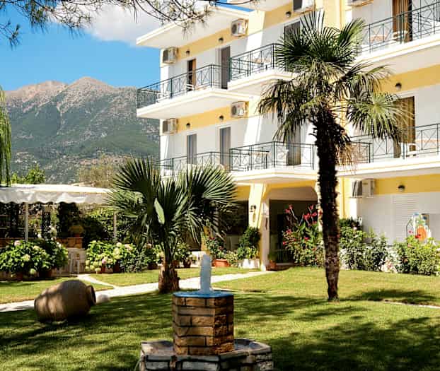 Hotellets have med grønne områder, en fontæne og bygningen i baggrunden. (AI-genereret tekst)