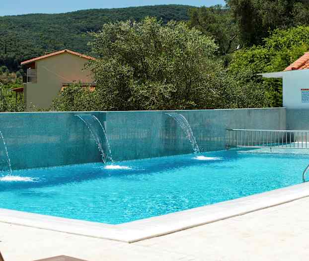 Udendørs pool med vandstråler og omkringliggende beplantning. (AI-genereret tekst)