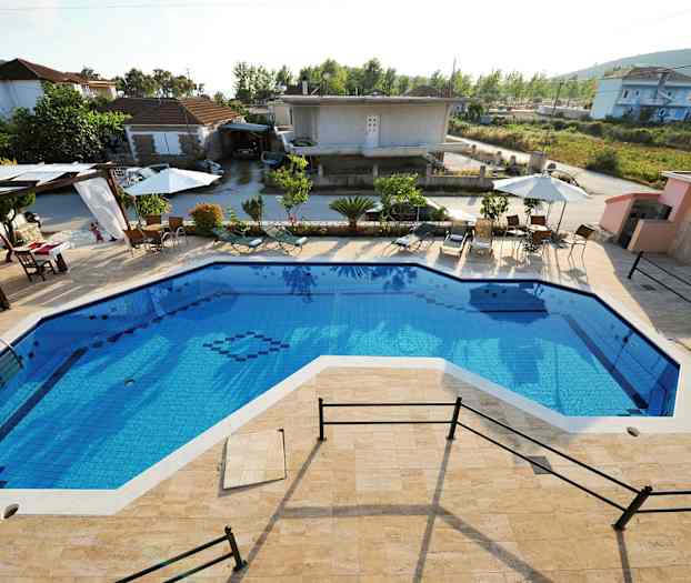 Udendørs pool med omkringliggende liggestole og parasoller samt bygninger i baggrunden. (AI-genereret tekst)