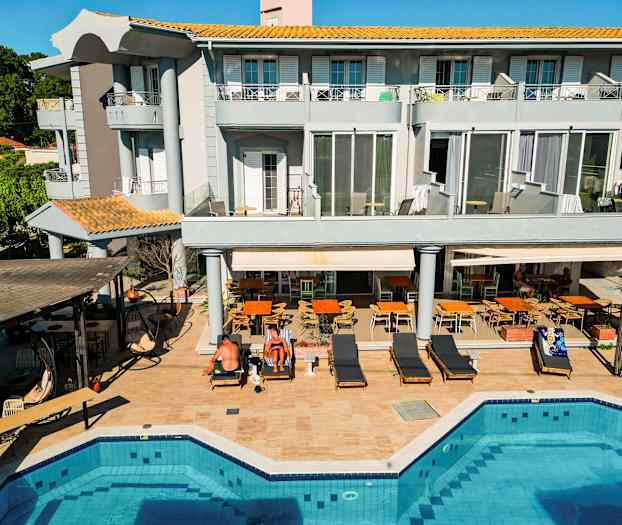 Et treetagers hotel ved en pool med omkringliggende liggestole og siddepladser. (AI-genereret tekst)