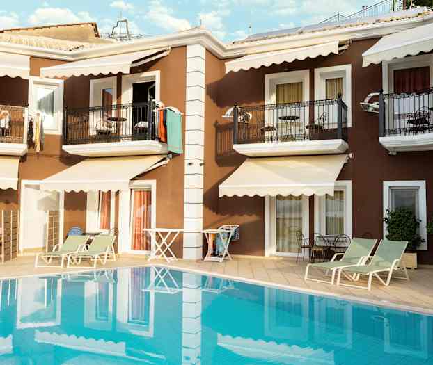 Lejlighedsbygning med altaner og liggestole ved poolen. (AI-genereret tekst)