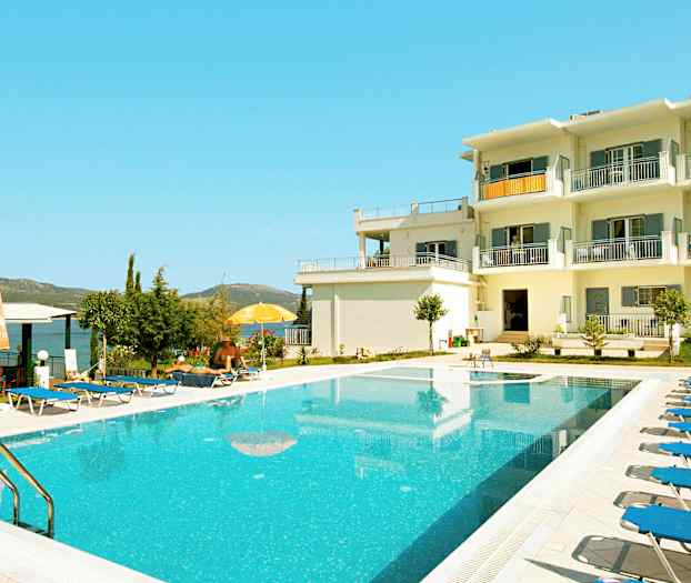 En udendørs pool ved en hvid bygning med altaner. (AI-genereret tekst)