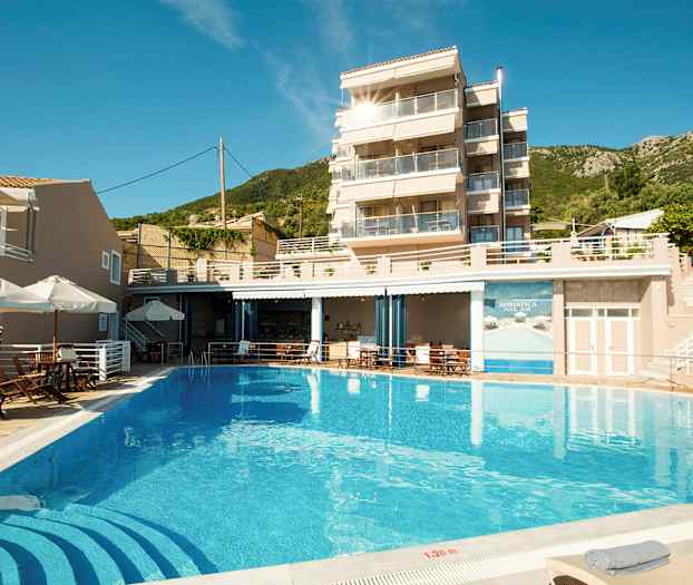 Billede af en bygning med glasbalkoner, en pool foran og liggestole omkring. (AI-genereret tekst)