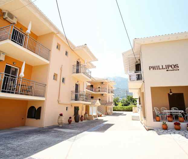 Bygninger med altaner og gennemgående beige facader samt dekorationer med blomster i potter. (AI-genereret tekst)