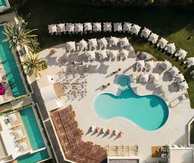 Luftfoto af et poolområde med liggestole og parasoller. (AI-genereret tekst)