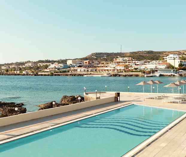 Billede af en pool med udsigt over havet og en kystby. (AI-genereret tekst)