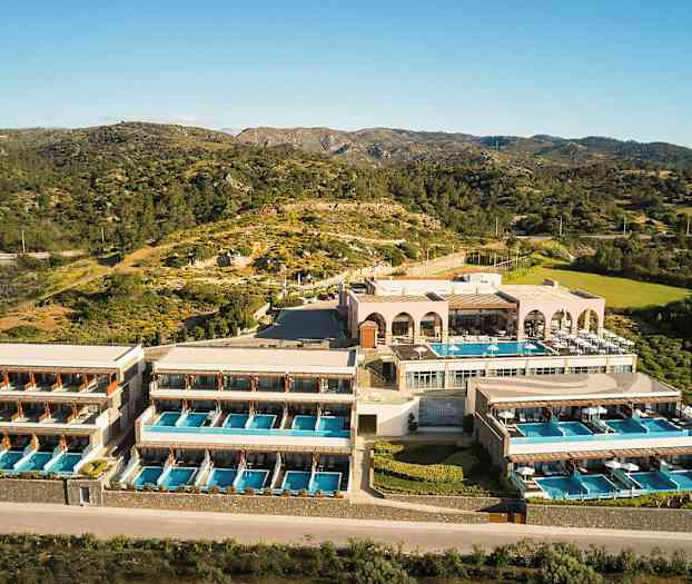 Hotelkompleks med flere bygninger og private pools, beliggende i naturligt landskab med bjerge og vegetation. (AI-genereret tekst)