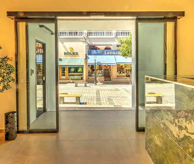 Udsigt fra receptionen mod gågade og butikker gennem glasdør. (AI-genereret tekst)