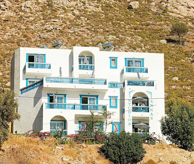 Hvid bygning med blå detaljer på en baggrund af råt landskab. (AI-genereret tekst)