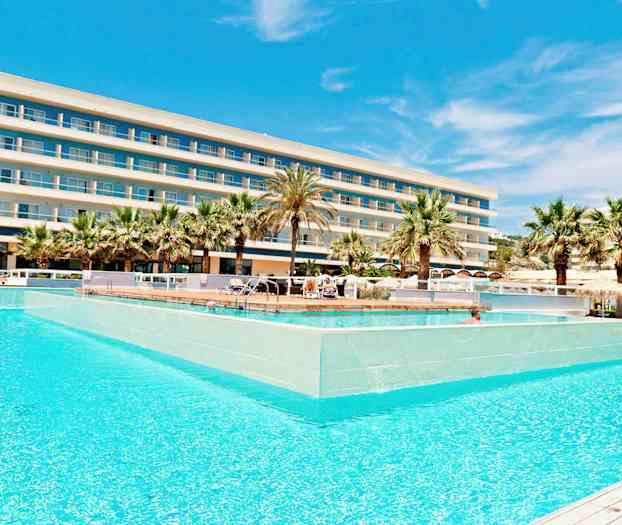 Et hotel med flere etager bag en stor pool omgivet af palmer. (AI-genereret tekst)