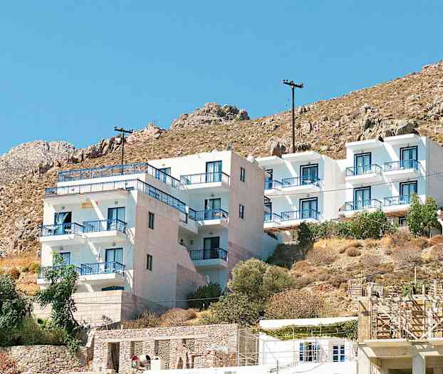 Hvid bygning med blå altanrækværk ved en bjergskråning. (AI-genereret tekst)