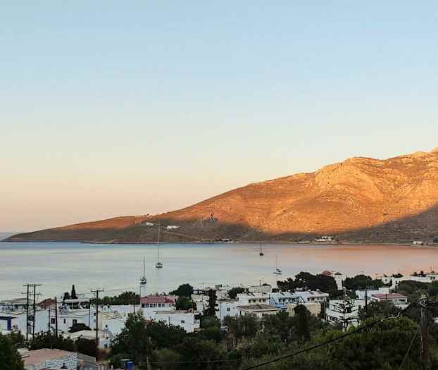 Strandby med sejlbåde og bjerge i baggrunden. (AI-genereret tekst)