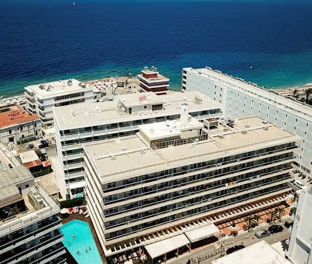 Luftfoto af hoteller og en strand ved havet. (AI-genereret tekst)