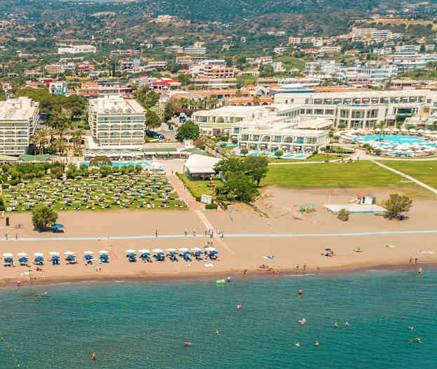 Hotelkompleks ved en sandstrand med liggestole og parasoller. (AI-genereret tekst)