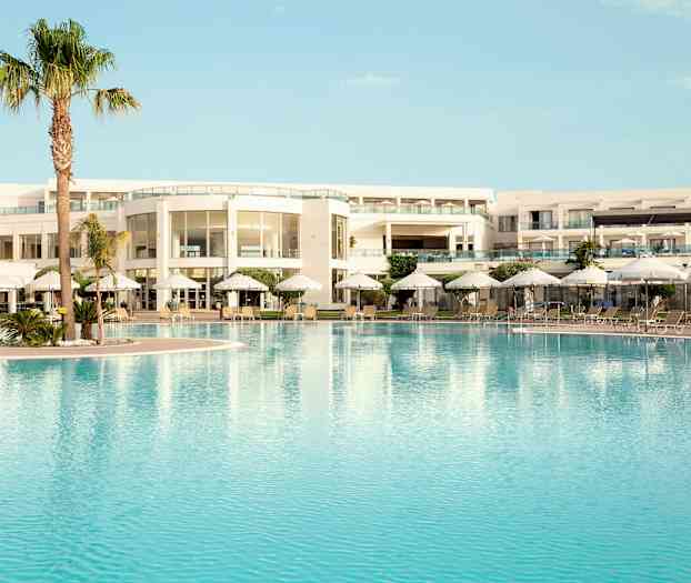 Poolområde ved en moderne hotelbygning med liggestole og parasoller. (AI-genereret tekst)