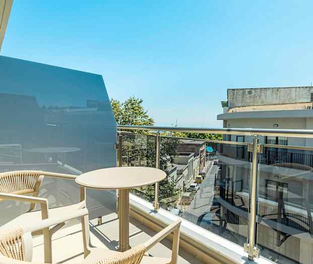 En altan med bord og stole i et bymiljø. (AI-genereret tekst)