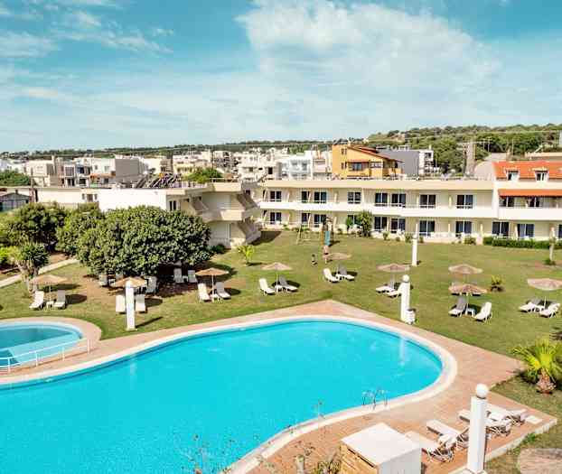 Et billede af en pool med liggestole og parasoller på en græsplæne, omgivet af bygninger. (AI-genereret tekst)