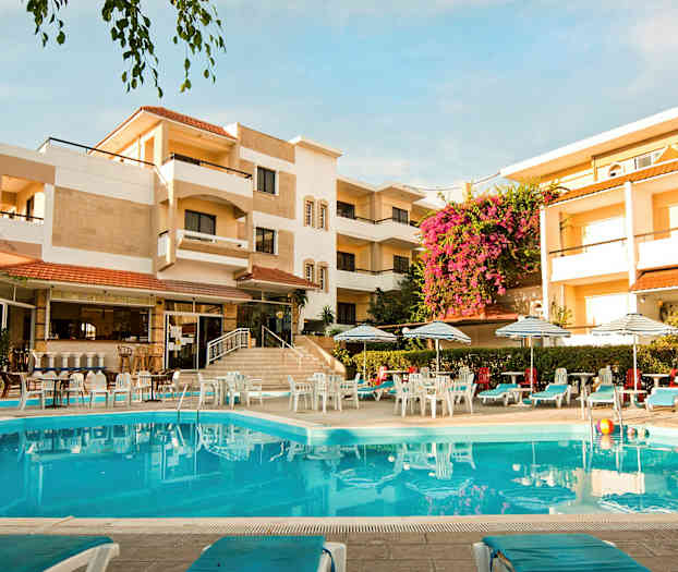 Hotelbygning med en pool i forgrunden, omgivet af liggestole og parasoller. (AI-genereret tekst)